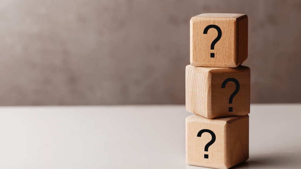 Drewniane klocki z pytajnikami symbolizujące refleksję i niepewność