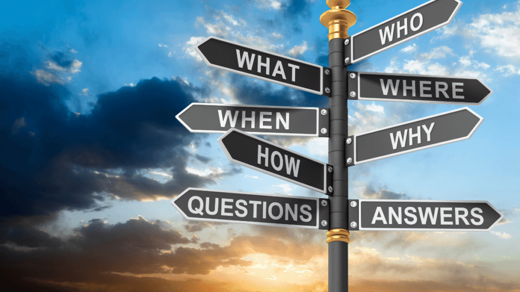 Tablica kierunkowskazów z pytaniami WHAT, WHO, WHERE, WHEN, WHY, HOW oraz ANSWERS na tle zachmurzonego nieba