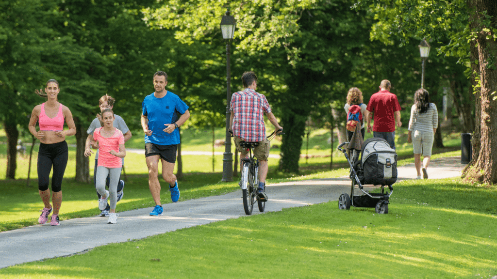 Aktywność fizyczna - ludzie biegają i jeżdżą na rowerze po zielonym parku